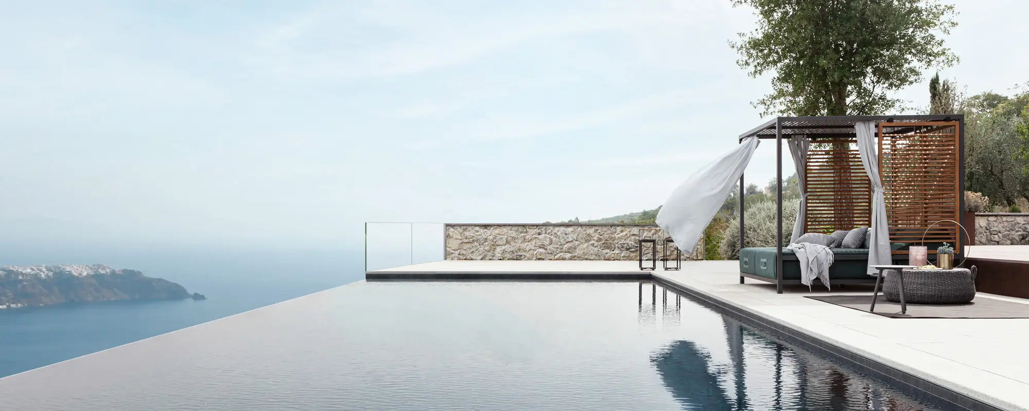 Luxury outdoor cabana daybed beside an infinity pool with panoramic sea view — modern coastal decor ideal for upscale outdoor living.