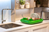 green dish rack with plates and cutlery next to kitchen sink, by marc newson for magis