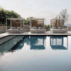Three Atmosphera Alcova daybeds placed in a lush ambience next to a pool.